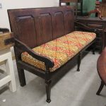 Antique settle (long-seat). Antique settle (long-seat) with large geometric long-cushion emphasising the wooden finish.