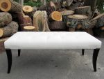 Shallow-buttoned long footstool. Shallow-buttoned long footstool covered in white faux leather.