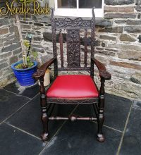A beautiful carved wooden chair with traditional upholstery and springs.
